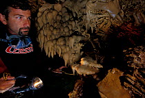 Diver in Deer Cave (grotta dei cervi), Alghero, Sardinia, Italy, looking at stalactites.