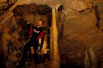 Diver looking at stalactites in Afitrite / Falco cave near Alghero, Sardinia, Italy.