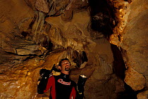 Diver looking at stalactites in Afitrite / Falco cave, near Alghero, Sardinia, Italy.