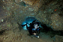 Divers in narrow passage in Ghost Cave (Grotta dei Fantasmi), Alghero, Sardinia.   Model released.