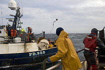 Crewmen preparing to pass across wires during paired trawler operations in the North Sea. October 2006.