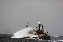 Fishing vessel heading into strong winds, towards an oil or gas rig in the distance. North Sea. October 2006.