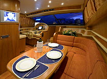 Table laid up for dinner in the seating and dining area, complete with flat screen television, of a luxurious Technema 65 motoryacht, built at the Rizzardi boatyard. Italy.