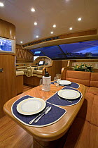 Table laid up for dinner in the seating and dining area, complete with flat screen television, of a luxurious Technema 65 motoryacht, built at the Rizzardi boatyard. Italy.