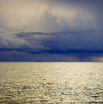 Boat on the horizon beneath a dark, low cloud in winter. Ragusa, on the southeast coast of Sicily, Italy.