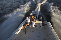 Couple relaxing on a Pursuit powerboat powering off the coast of Annapolis, Maryland, USA.