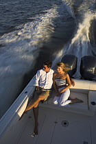 A couple relaxing on the back of a Pursuit powerboat, powering off the coast of Annapolis, Maryland, USA.