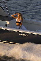 Woman relaxing on the back of a Pursuit powerboat travelling at speed off the coast of Annapolis, Maryland, USA.