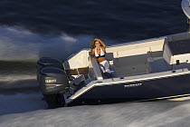 A woman relaxing on the back of a Pursuit powerboat travelling at speed off the coast of Annapolis, Maryland, USA.