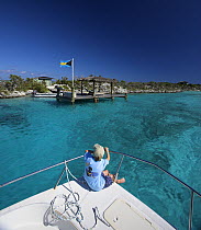 Young boy sitting on deck of Shannon Shoalsailor, this innovative beachboat is a shallow draft boat designed to roam shallow waters such as these, Exuma, Bahamas.