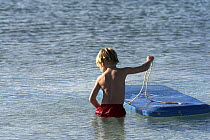 A little boy playing in the shallow waters with a boogie board, Exuma, Bahamas.