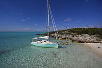 Shannon Shoalsailor moored alongside a sandy beach with a family in the water. This innovative beachboat is a shallow draft boat designed to roam shallow waters such as these in Exuma, the Bahamas.
