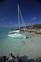 Shannon Shoalsailor moored alongside the shore with a family in the water. This innovative beachboat is a shallow draft boat designed to roam shallow waters such as these in Exuma, the Bahamas.