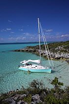 Shannon Shoalsailor moored alongside the shoreline with a family playing in the water. This innovative beachboat is a shallow draft boat designed to roam shallow waters such as these in Exuma, the Bah...