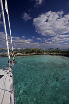 Young girl standing at the bow of an anchored Shannon Shoalsailor yacht. This innovative beachboat is a shallow draft boat designed to roam shallow waters, Exuma, Bahamas.