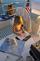 A child colouring on board a Shannon Shoalsailor yacht, Exuma, Bahamas.