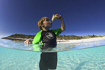 Young boy kissing a shell he has found in the shallow waters of Exuma, Bahamas.