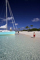 A Shannon Shoalsailor moored by a sandy beach with a family. This innovative, keelless, shallow draft beachboat is designed to roam shallow waters such as these in Exuma, the Bahamas.