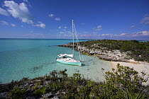 Shannon Shoalsailor moored alongside a sandy beach with a family in the water. This innovative beachboat is a shallow draft boat designed to roam shallow waters such as these in Exuma, the Bahamas.