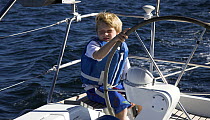 Little boy taking the wheel on cruising yacht, Mexico.