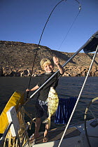 Young boy on board a boat, having caught a fish on his fishing line, Los Islotes, Mexico. Model released.