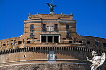 View of the Castel Sant'Angelo with angel statue in foreground, Rome, Italy. ^^^The castle is also known as the Mausoleum of Hadrian as it was commissioned by the Roman Emperor Hadrian as a mausoleum for himself and his family. The building spent over a thousand years as a fortress and castle and is now a museum.