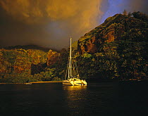 Dramatic clouds at sunset over a catamaran anchored in the Bay of Virgins in the Marquesas Islands, French Polynesia.