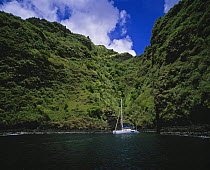 Catamaran cruising the coast of the Marquesas Islands, French Polynesia.