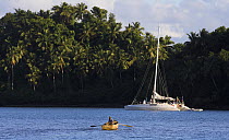 Rowing back to a sailboat anchored on the palm tree lined coast of Dominican Republic, Caribbean.
