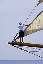 The bowman standing on the bow sprit of classic wooden boat at the St. Barths Bucket Regatta, St Barthelemy, Caribbean.