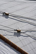 Wooden blocks that form part of the rigging system of the peak halyard of the top sail, resting against the mainsail of a gaff rigged classic boat, St. Barths Bucket Regatta, St Barthelemy, Caribbean.