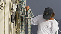 A crew member coiling up the line after a day of racing, St Barths Bucket Regatta, St Barthelemy, Caribbean.