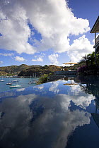 Clouds in the sky reflect off the still waters of an infinity pool overlooking the harbour in Gustavia, St. Barthelemy, Caribbean.