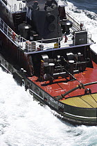 A tugboat pulling a barge into Narragansett Bay in Newport, Rhode Island, USA.