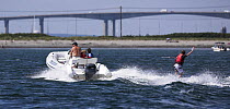 A father and children in a hard bottom inflateable out wakeboarding in front of Jamestown Bridge, Jamestown, Rhode Island, USA.