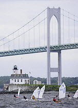 Dinghy fleet sailing by Newport Bridge and Rose Island Lighthouse during the Optimist regatta, Newport, Rhode Island, USA.