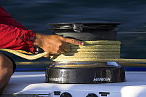 Crew member onboard "Maximus" holding a wrapped sheet around a winch during the 2006 Newport to Bermuda Race. Property Released.