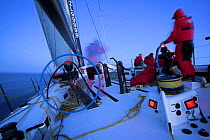 Maximus continues to race after dusk with a man at the helm and crew on the rail during the 2006 Newport to Bermuda Race. Model and Property Released.