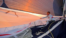 The bowman onboard "Maximus" bringing in the spinnaker at takedown as the morning sun begins to rise during the 2006 Newport to Bermuda Race.