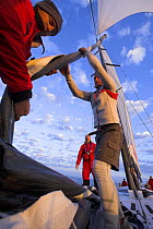 The crew onboard "Maximus" furling the jib sail while the spinnaker is flying during the 2006 Newport to Bermuda Race.