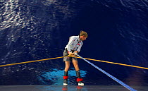 Crew member on board "Maximus", standing on the side of the hull to check the keel for seaweed during the Newport to Bermuda, 2006.