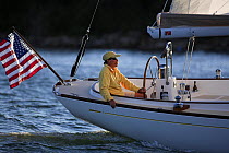 A man on board a Morris 42 cruising in the evening, Newport, Rhode Island, USA.