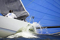 Crew on board a 12m yacht gathering in the foresail during a race.
