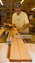 Young man planing planks of wood for boat construction.