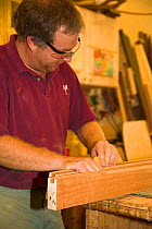 Man sanding planks of wood for boat construction.