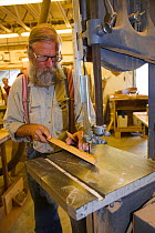 Man sawing a piece of wood for boat construction.