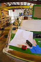 Plans and tape measure on deck of a boat under construction.