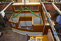 Interior boat section being lowered into the hull of a yacht under construction.