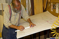 Man drawing out plans for a yacht under construction.