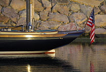 Transom of a small cruising yacht anchored near harbour wall.